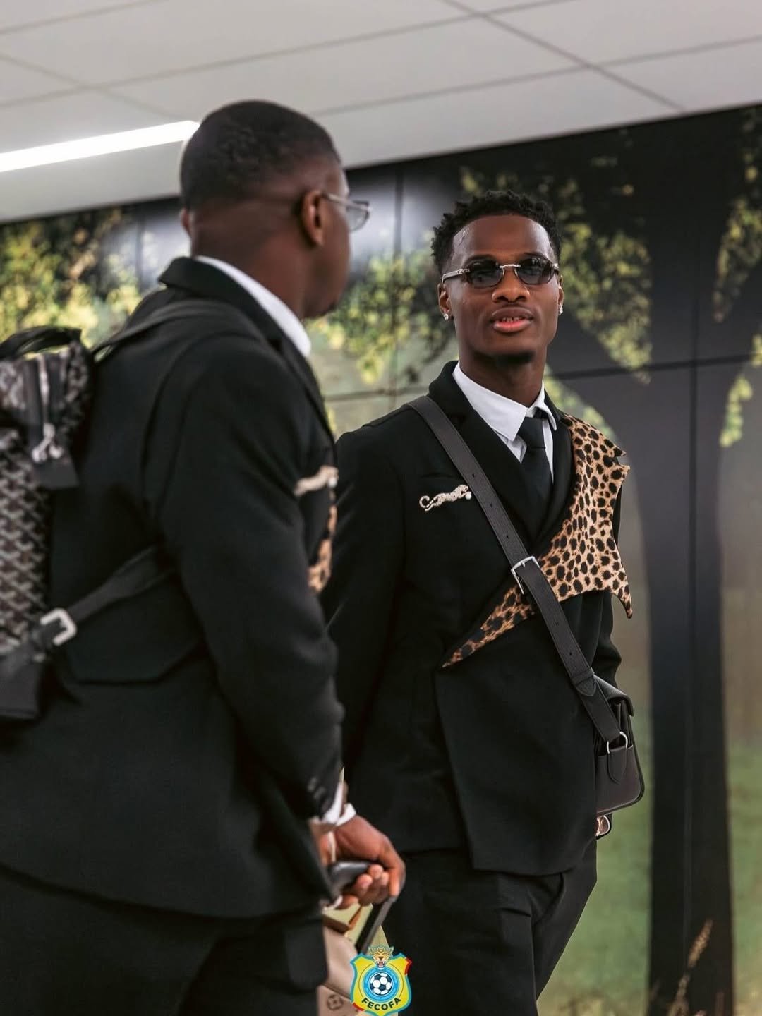 Two members of the Democratic Republic of Congo national team wearing black tailored suits with leopard-print panels