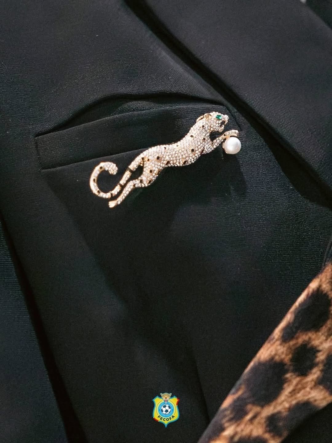 Close-up of a leopard brooch pinned to black tailoring with leopard-print fabric detail